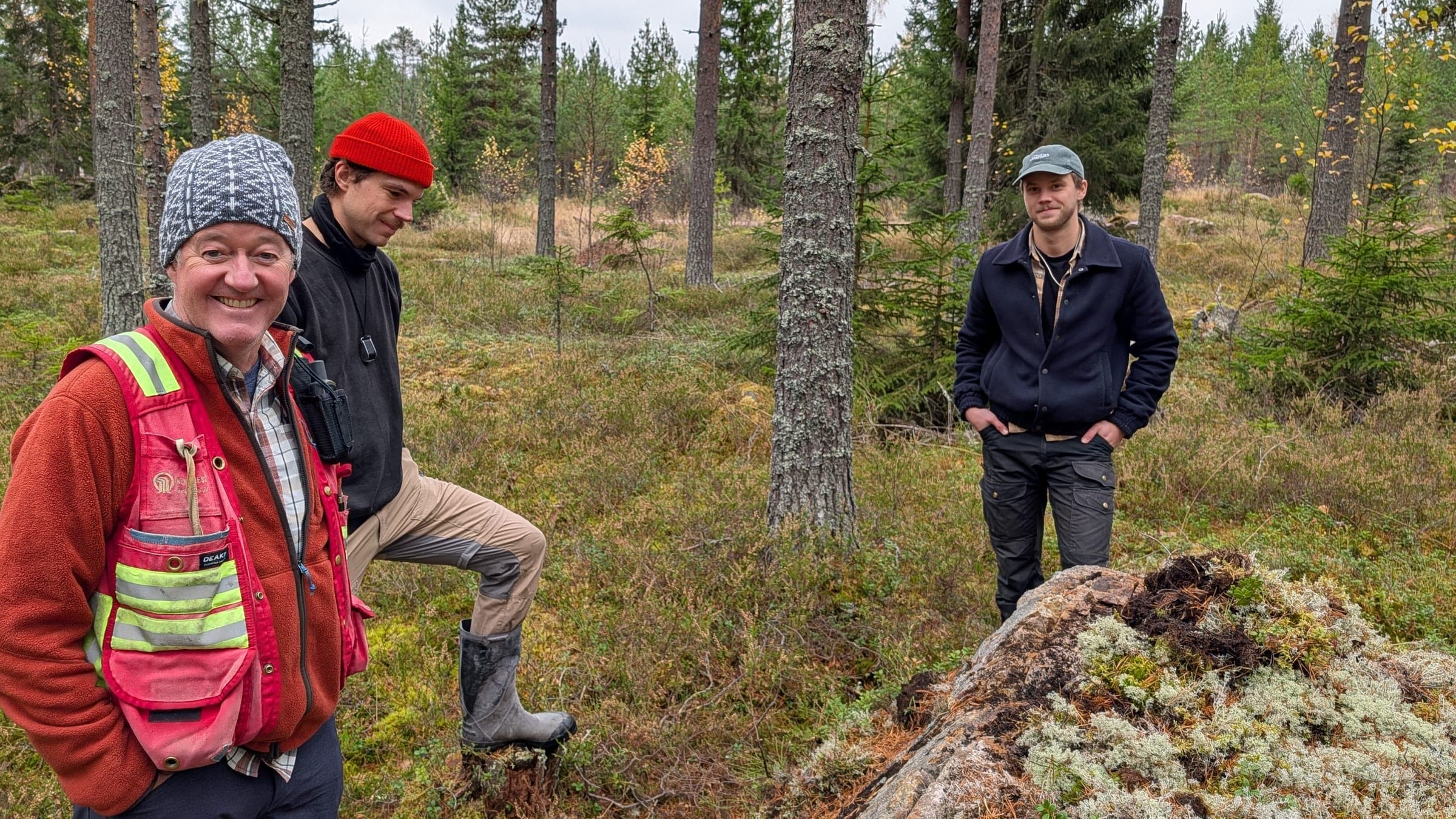 Three members of our field team in a pine forest, beside a lichen-covered rock outcrop.
