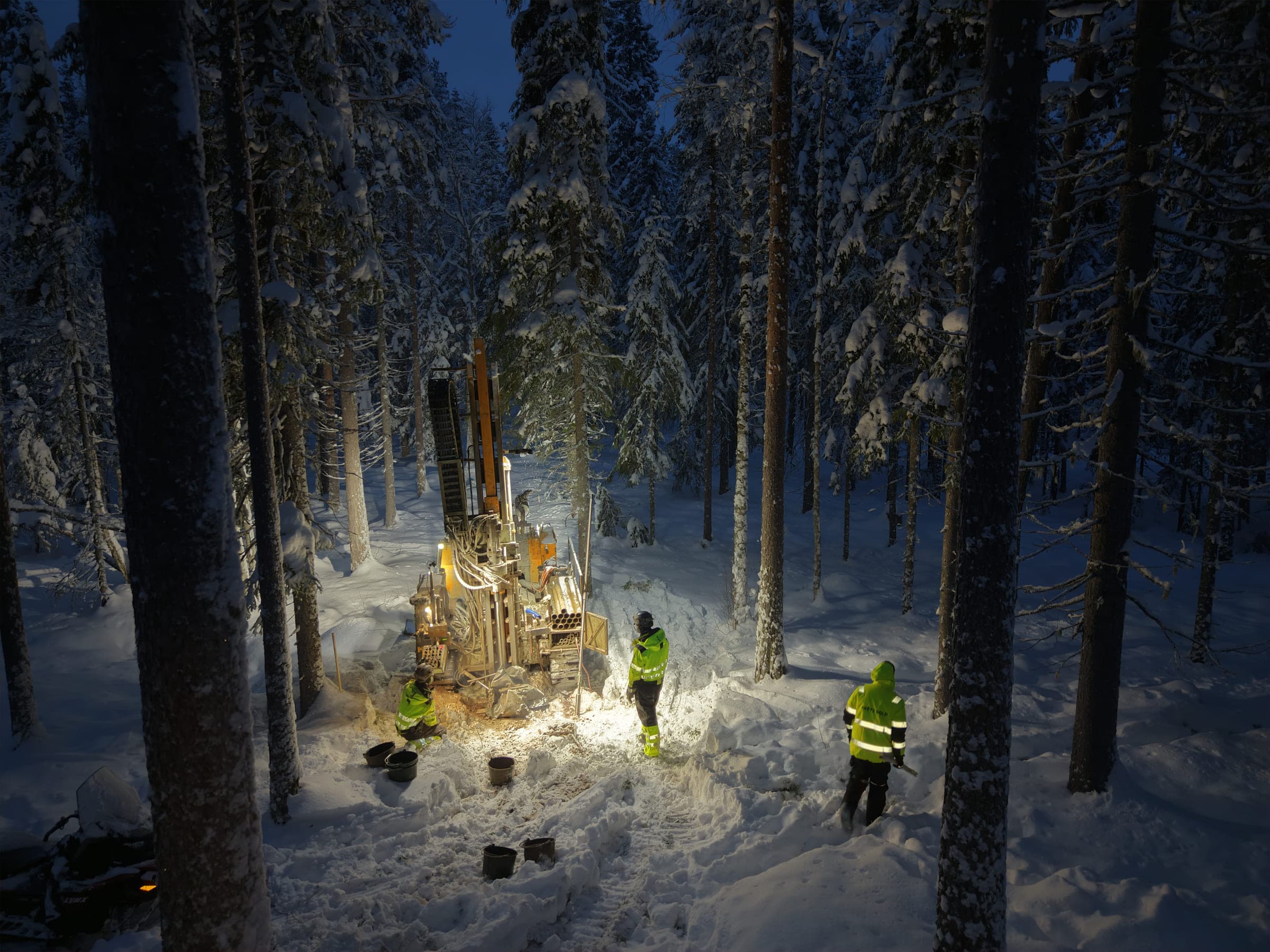 Diamond drill rig working at night among snow-covered pines