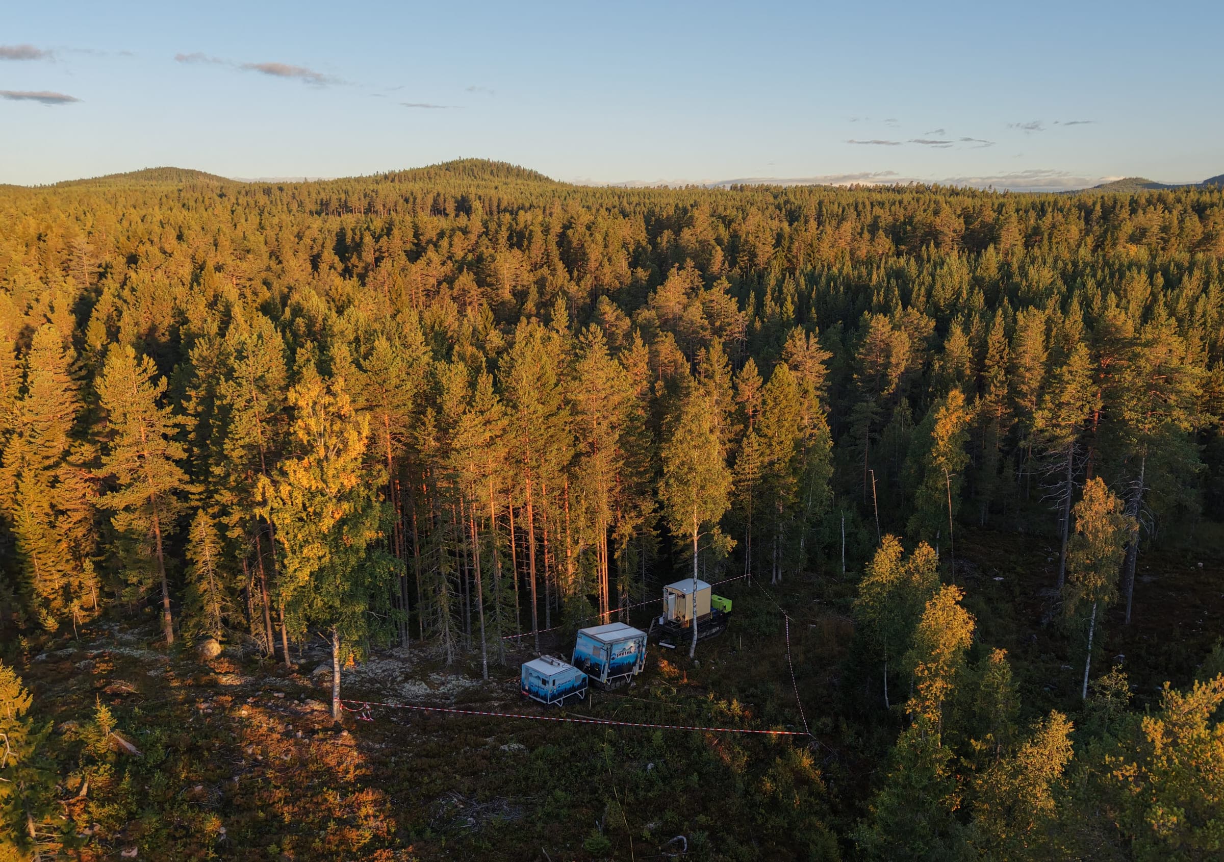 Drill rig and site cabins in the forest at sunset, seen from above
